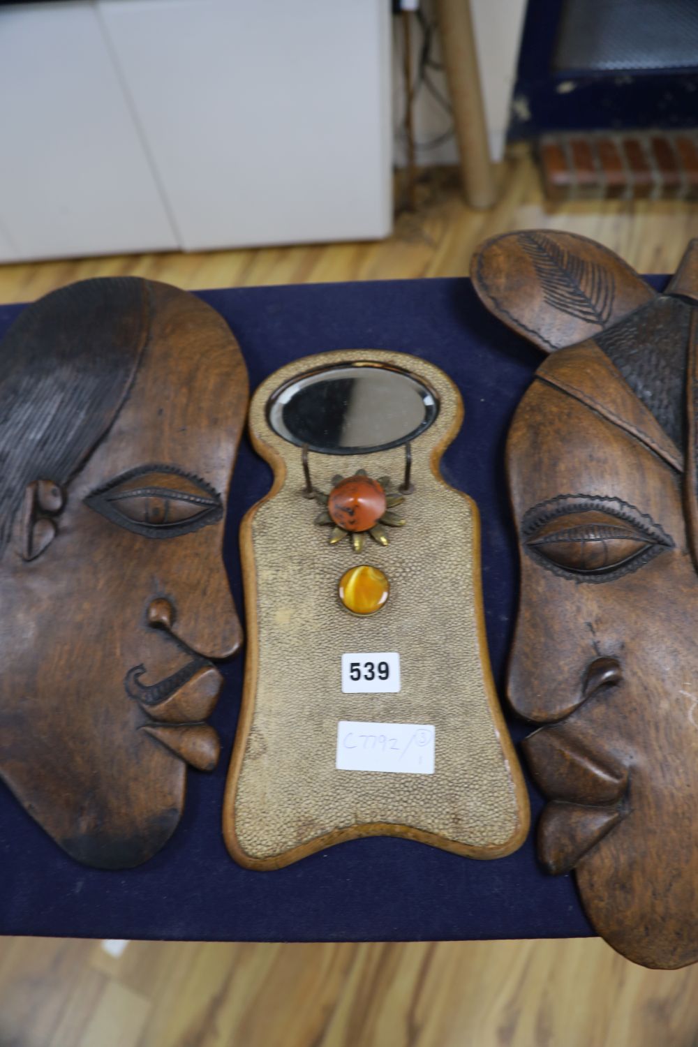 Two carved wooden face masks and a shagreen mirror